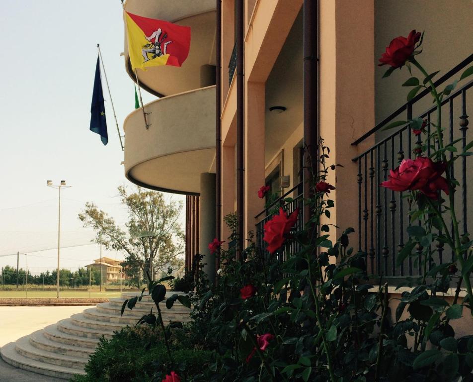 un edificio con rosas rojas y una bandera en él en Hotel Villa Damanti, en Licata