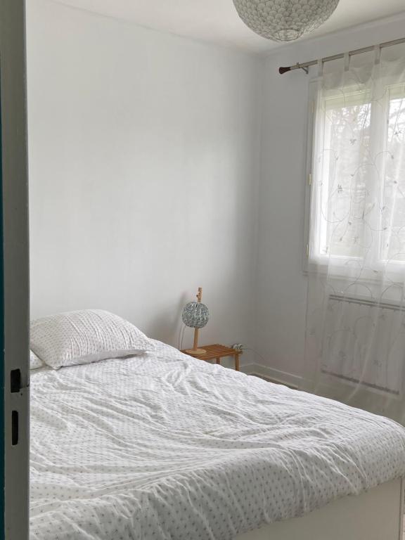 Habitación blanca con cama y ventana en Maison avec jardin proche de Paris et à 20 min de Disney, en Tournan-en-Brie