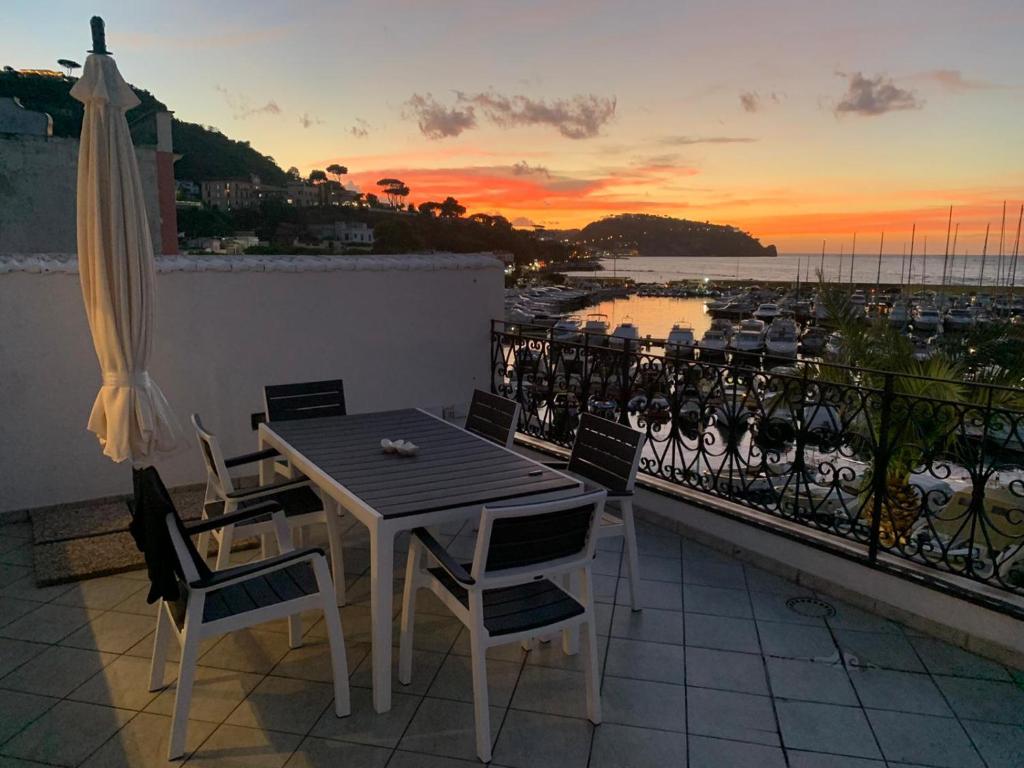 uma mesa e cadeiras numa varanda com um pôr-do-sol em Exclusive apartment Piccola Marina em Ischia