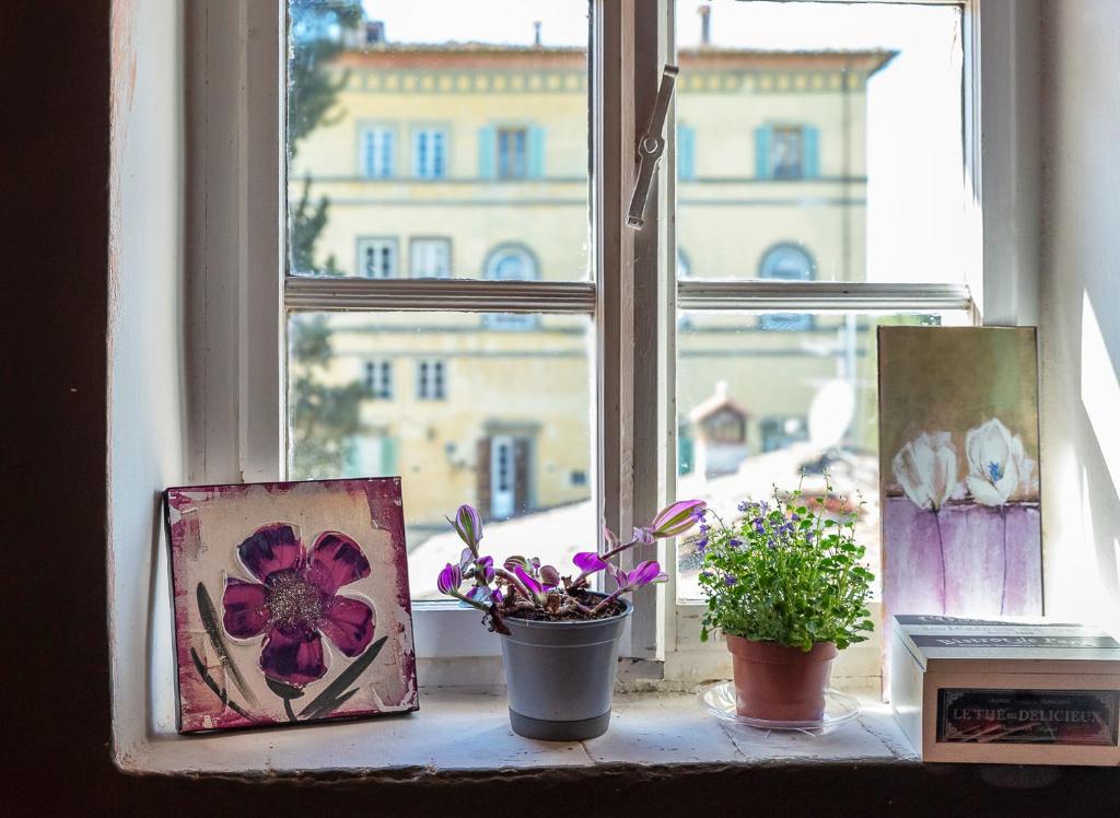 a window with two paintings and flowers on a window sill at NEW! La Stanza in Villa in Lucca