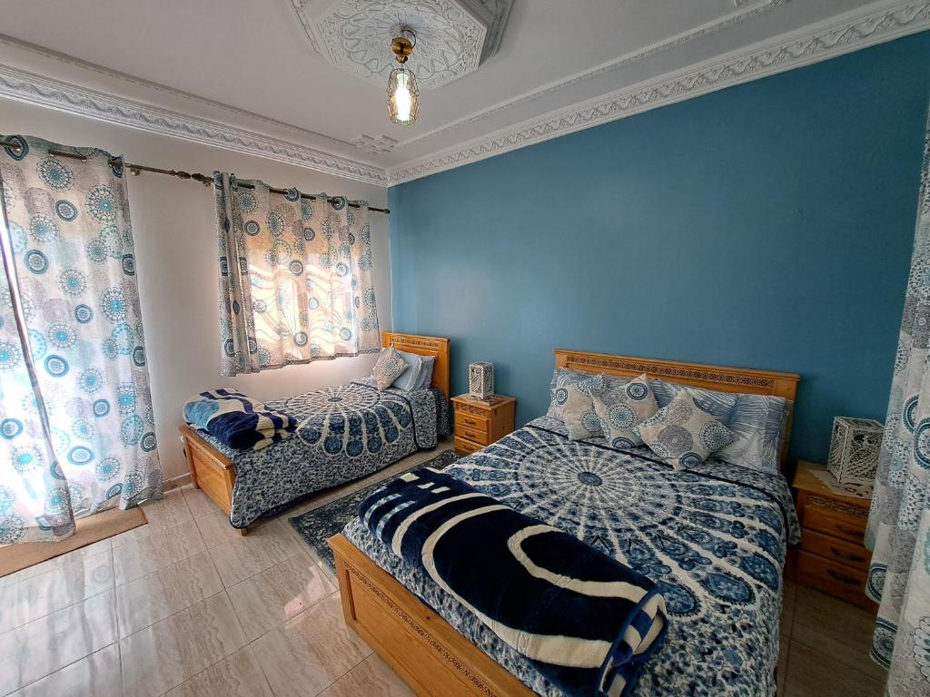 um quarto com 2 camas e paredes azuis em Diafa em Tânger