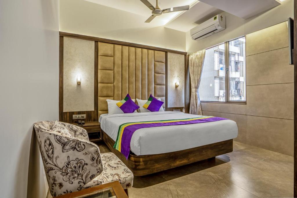 a bedroom with a king sized bed and a chair at Treebo Tryst Savera Inn in Mumbai