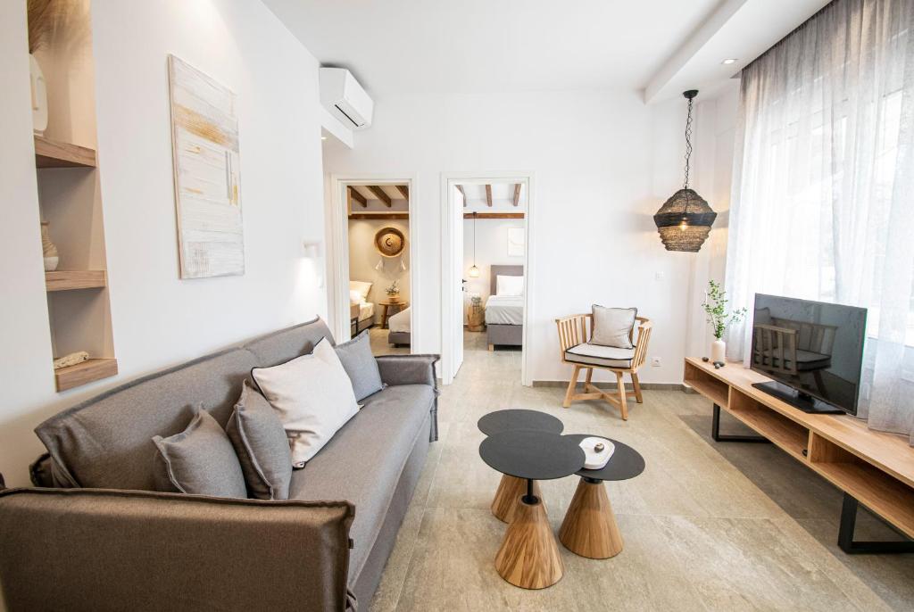 Coel Luxury Suites by RentalsPro Services - Potidea Halkidiki في نيا بوتيدايا: غرفة معيشة مع أريكة وتلفزيون