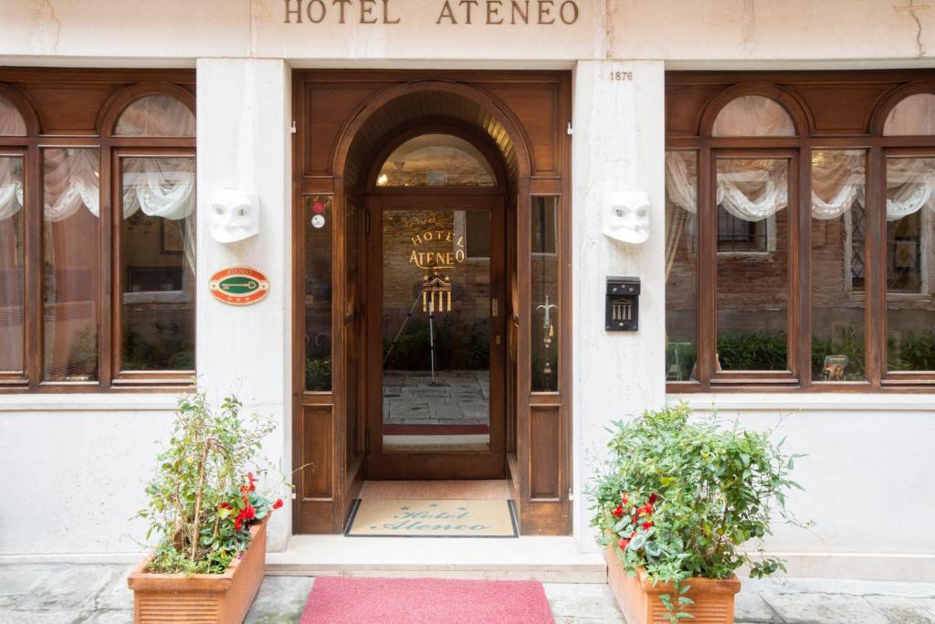 a hotel entrance with a wooden door and two plants at Hotel Ateneo in Venice