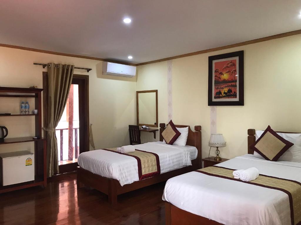 ルアンパバーンにあるXayana Home Villasのベッド2台と窓が備わるホテルルームです。