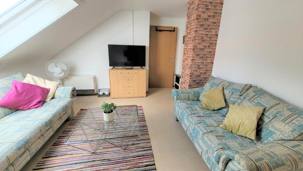 a living room with two couches and a tv at Ferienwohnung am Schwarzwaldrand in Nagold