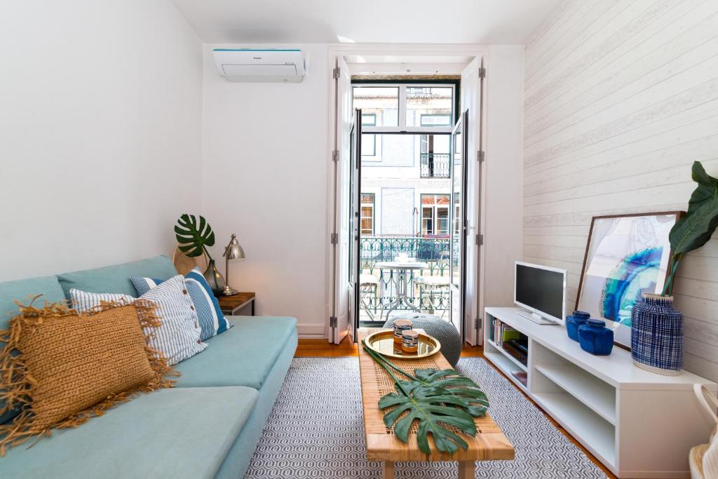 een woonkamer met een blauwe bank en een tv bij Chic Urban Apartment at Downtown with a Sunny Balcony! in Lissabon