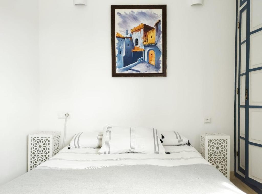 a bedroom with a bed and a painting on the wall at Maison Médina, terrasse panoramique, vue mer in Tangier