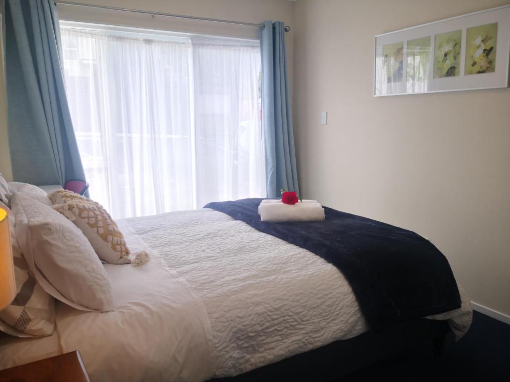 a bedroom with a bed with a large window at Rose Room in Auckland