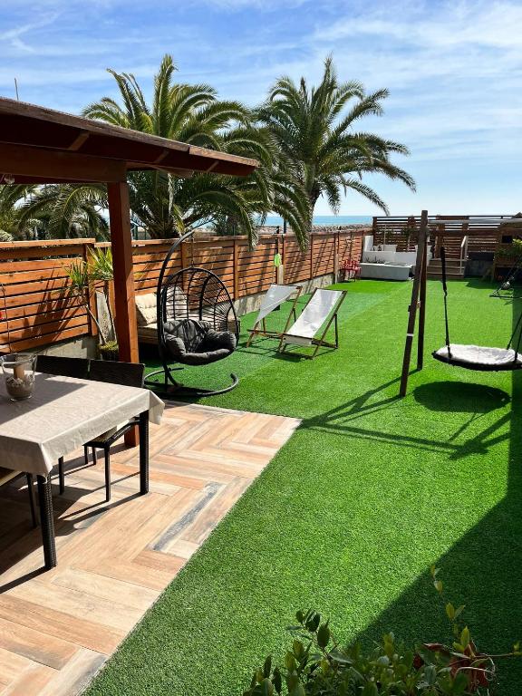 a patio with a lawn with chairs and a table at Casa en primera linea de playa in Puzol