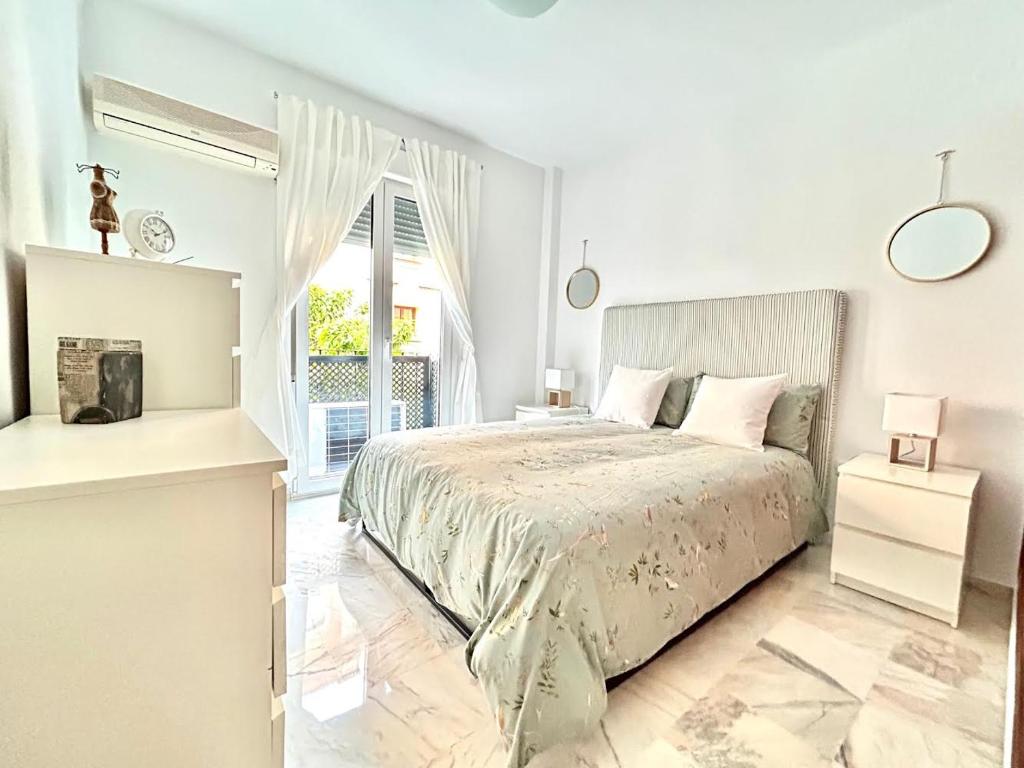 a white bedroom with a bed and a window at Hispalis Triana in Seville