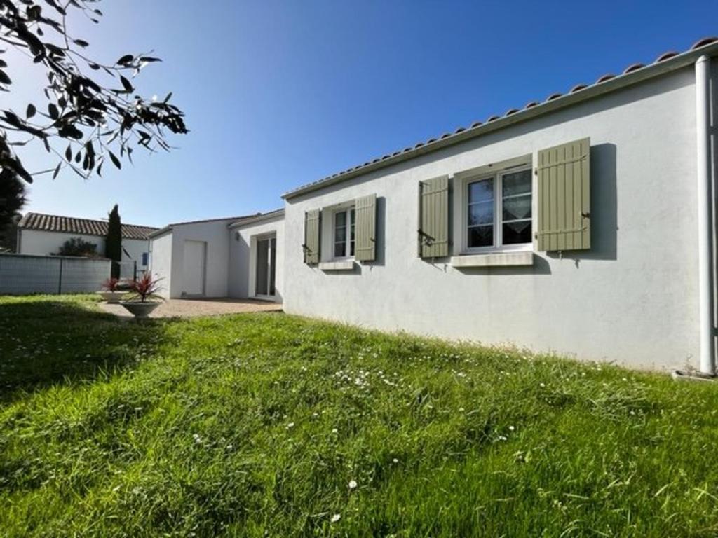 une maison blanche avec des fenêtres vertes et une cour dans l'établissement Maison lumineuse avec jardin clos et WIFI – 6 couchages, Saint-Georges-d'Oléron - FR-1-246A-199, à Saint-Georges-dʼOléron