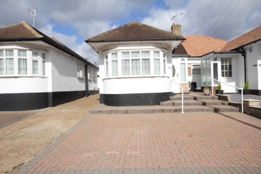 a row of white houses with a brick driveway at The Ruislip Bungalow in Ruislip