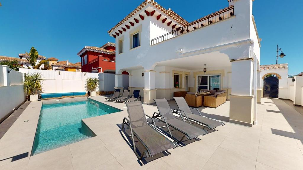 a villa with a swimming pool and chairs at Villa Cerezo - A Murcia Holiday Rentals Property in Torre-Pacheco