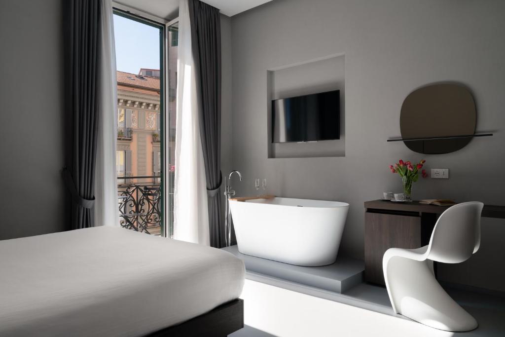 a bedroom with a tub and a bed and a tv at The Grey in Naples
