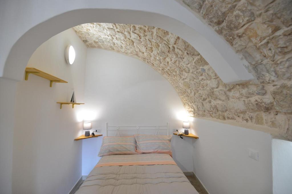 a bed in a room with a stone wall at B&B CASAVACANZE CHIESA MADRE in Carovigno