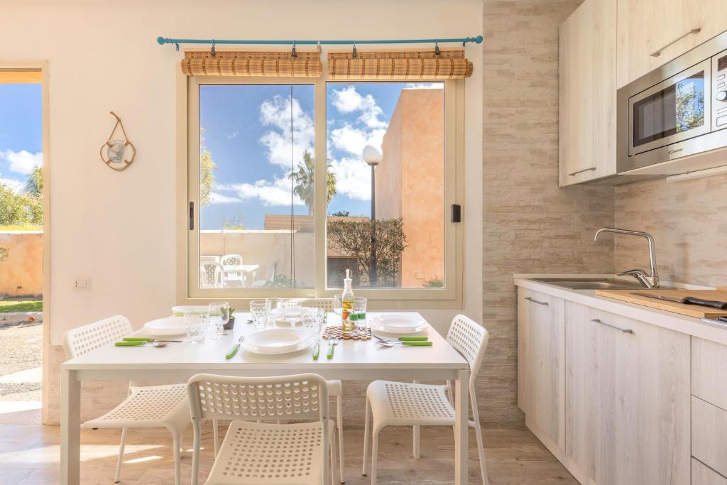 einen weißen Tisch und Stühle in einer Küche mit Fenster in der Unterkunft Free Beach House - 50 mt from the beach in Costa Rei