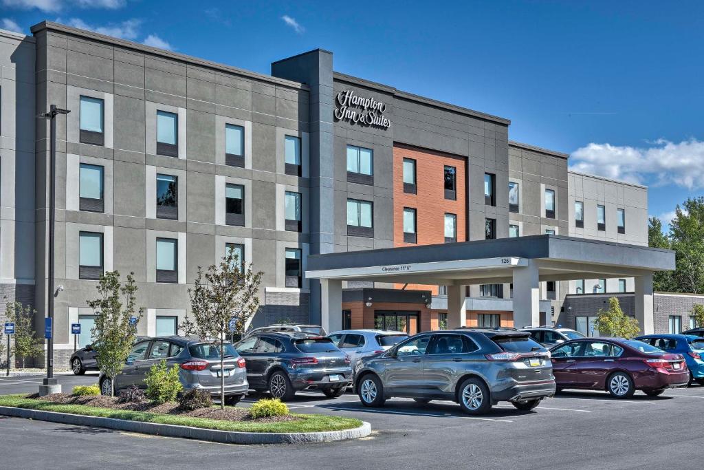 Un edificio con coches aparcados en un estacionamiento. en Hampton Inn &amp; Suites Keene, en Keene