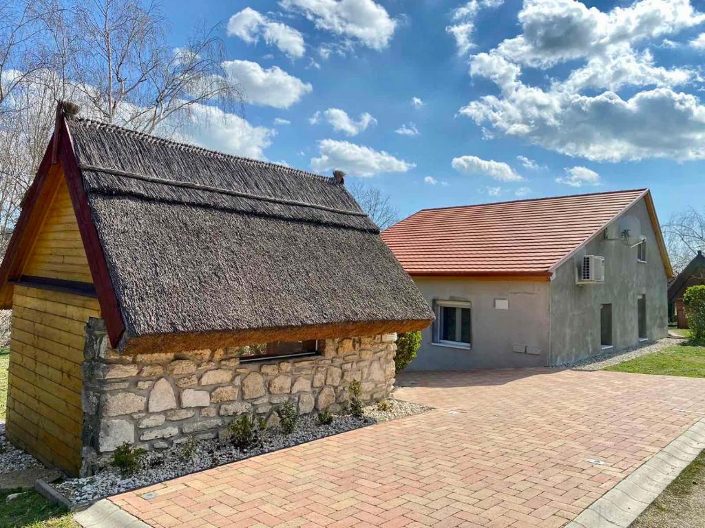 a house with a stone building and a brick driveway at Bene Vendégház in Szigliget