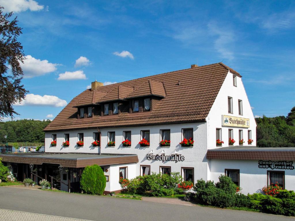 a white building with a brown roof at Pension Buschmühle in Ohorn