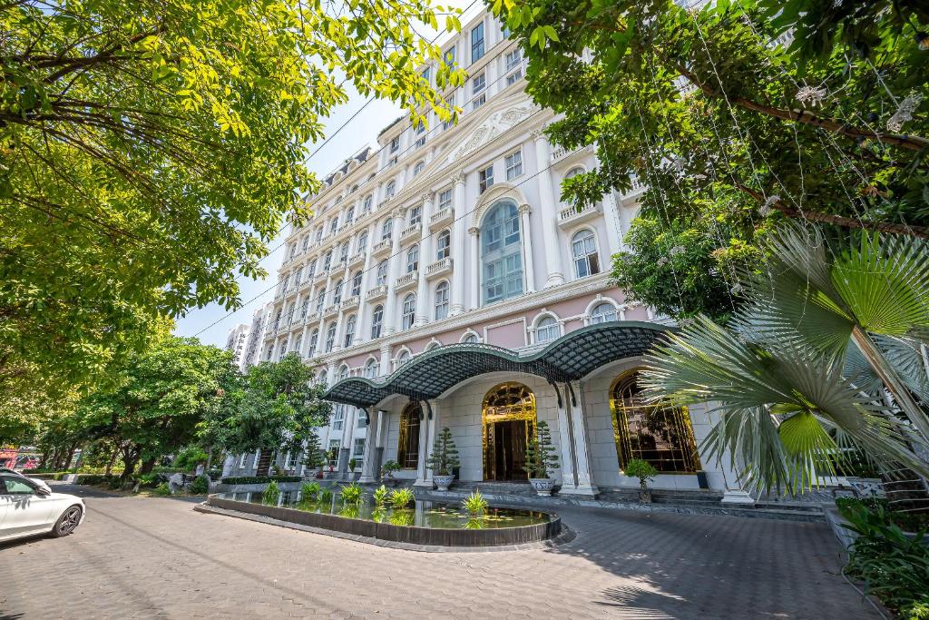 a large white building on a street with trees at Cozrum Homes - Sonata Residence in Ho Chi Minh City