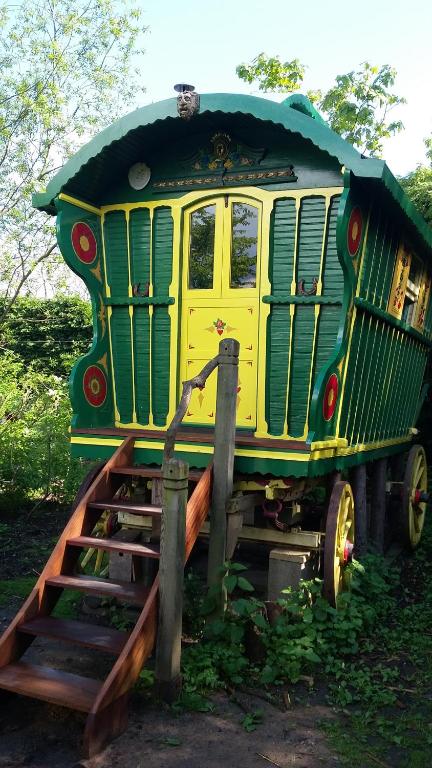 a green and yellow train car sitting on a ramp at Gypsy Caravan at Alde Garden in Saxmundham