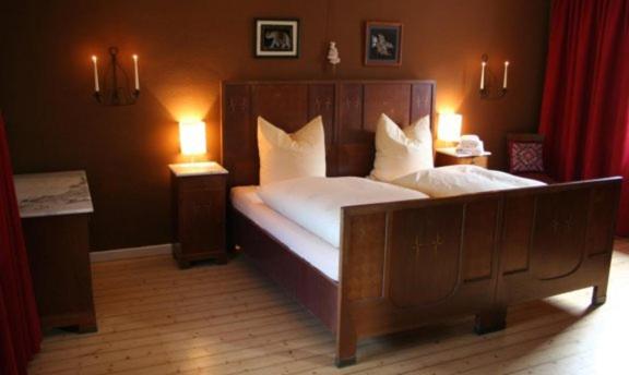 a bedroom with a large wooden bed with two lamps at McMüller's Brauereigasthof in Kofferen