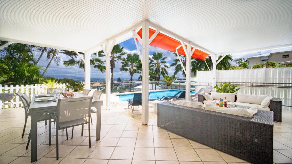 une terrasse avec un canapé, une table et une piscine dans l'établissement Villa K'Line - Piscine privée, magnifique vue mer aux Trois-Ilets, à Les Trois-Îlets
