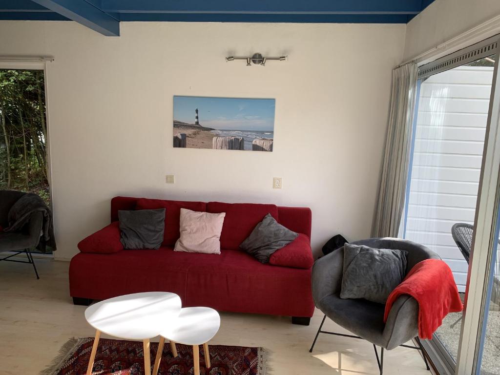 een woonkamer met een rode bank en een tafel bij Kustverhuur, Park Schoneveld, Zeester 68 in Breskens