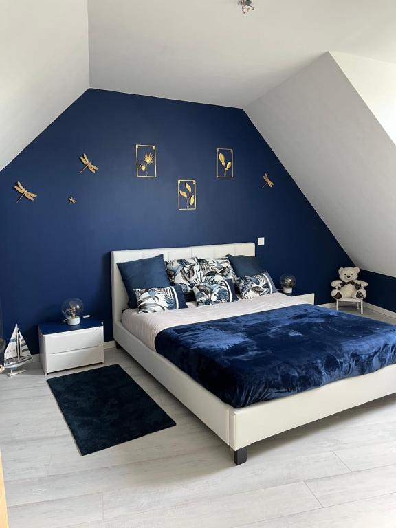 a bedroom with a bed with a blue wall at La fleur des marais in Batz-sur-Mer