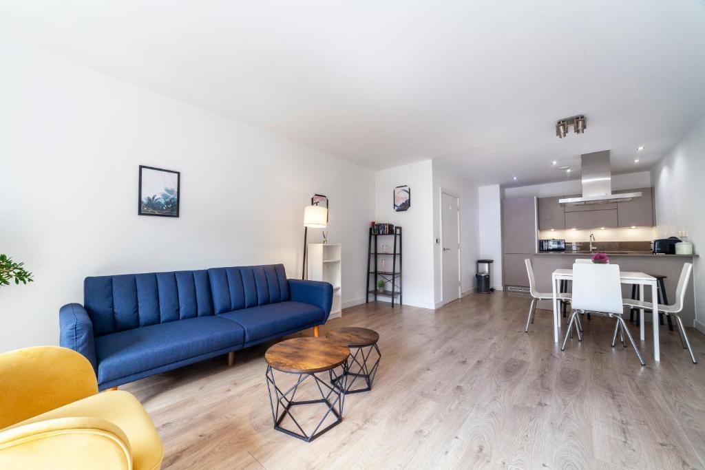a living room with a blue couch and a kitchen at Modern 3BDR Flat w large balcony, Kentish Town in London