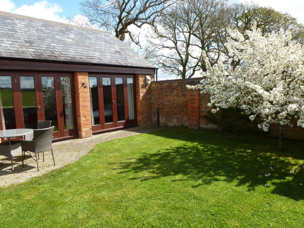 a garden with a table and a tree with white flowers at Smallthorns Barn in Market Harborough