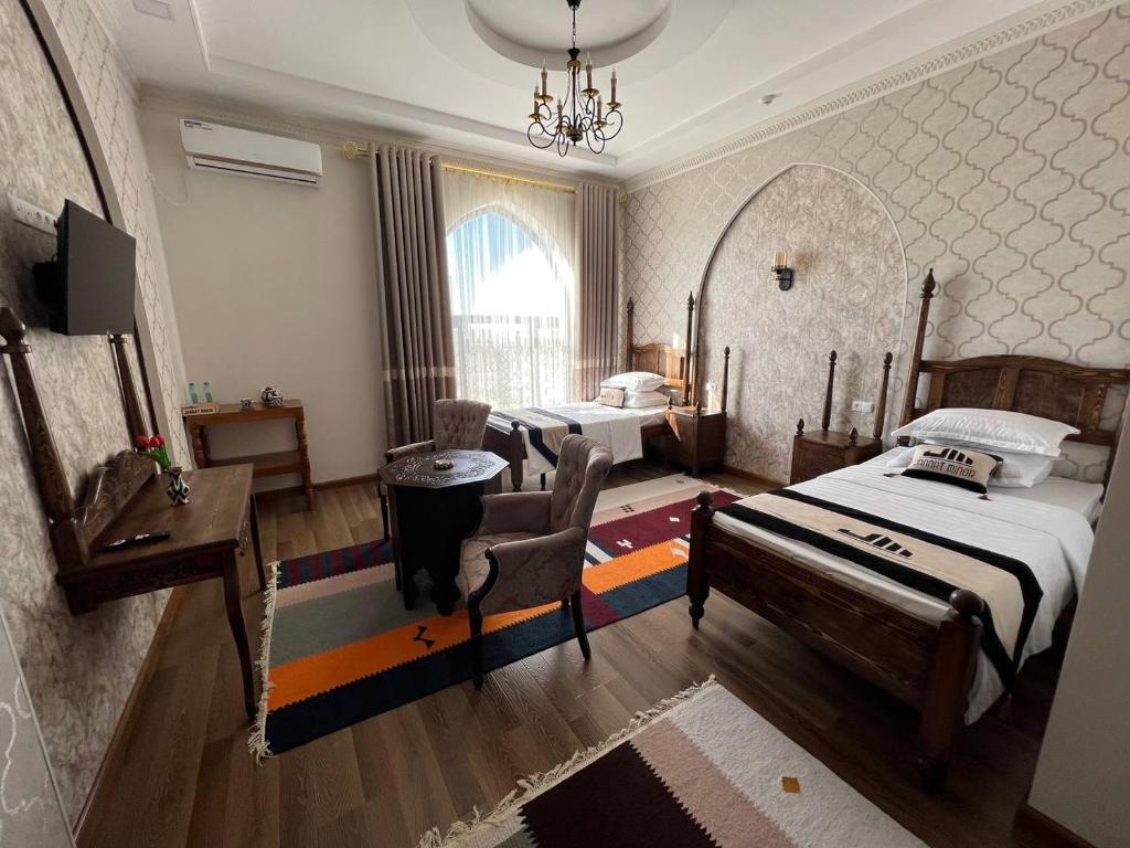 a bedroom with two beds and a desk and a mirror at Jannat Minor Boutique Hotel in Urganch