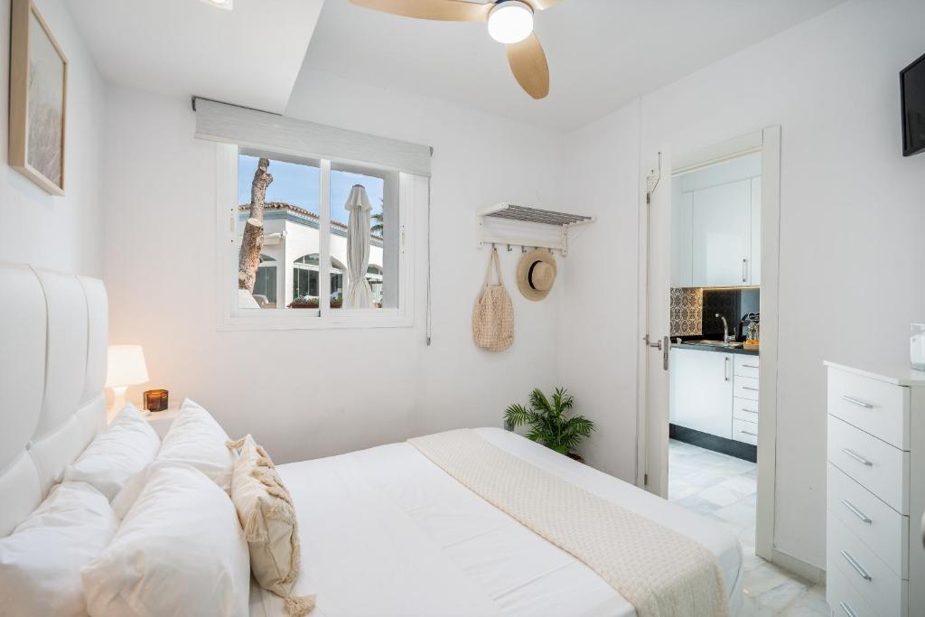 a white bedroom with a bed and a kitchen at Casa Hibiscus Marbella in Marbella