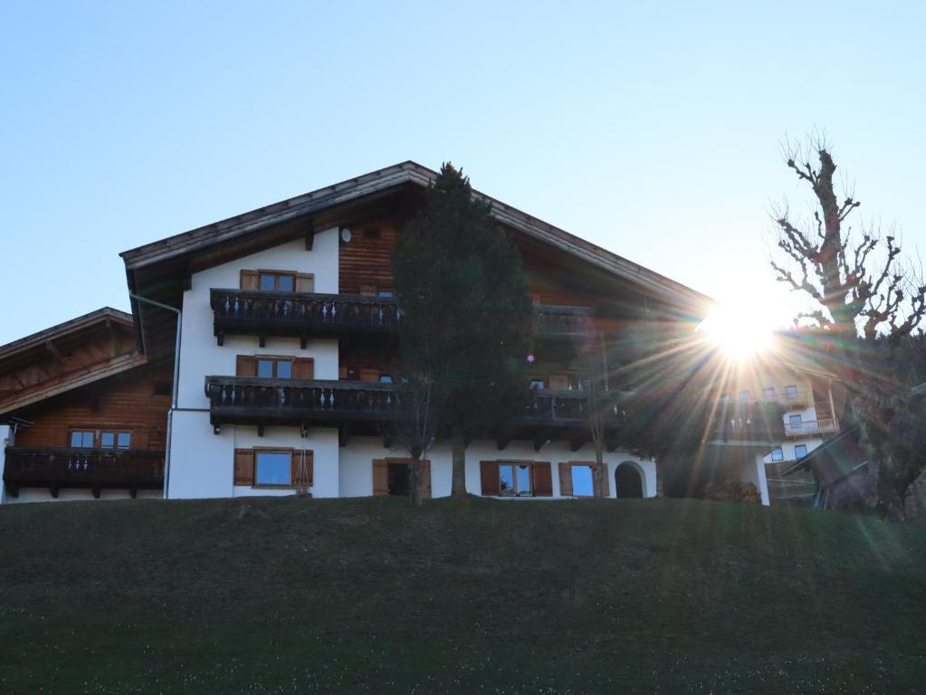 a building on a hill with the sun behind it at Portnerhof auf Oberkirn in Schenna