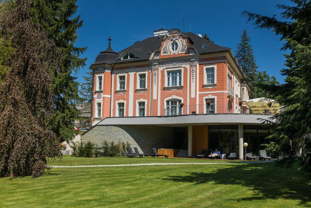 a large brick building with a clock on top of it at Wellness & Spa hotel Villa Regenhart in Jeseník