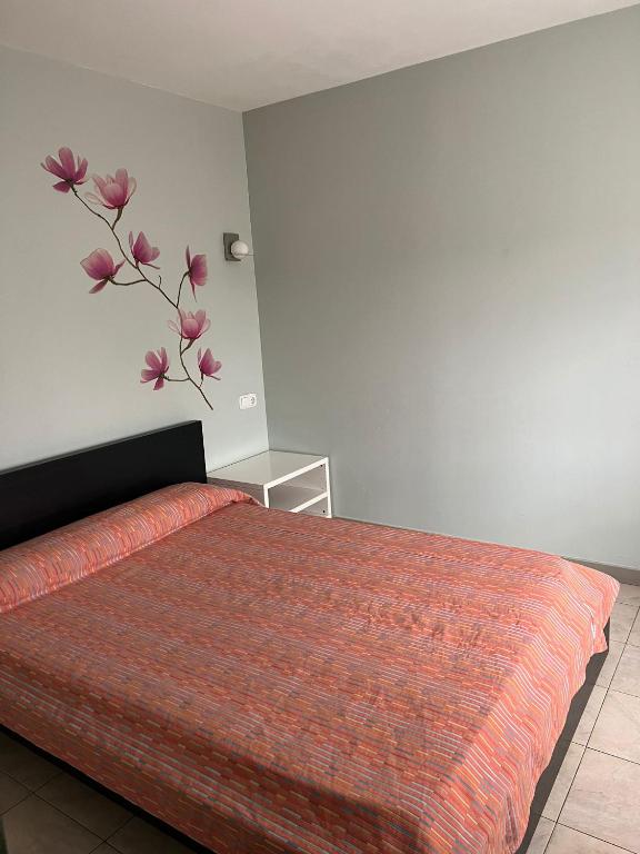 1 dormitorio con 1 cama con una flor en la pared en Hostal - Restaurante Asador Esperanza en Huesca