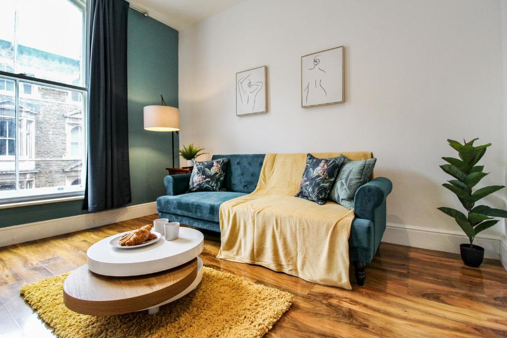 a living room with a blue couch and a table at Sleek & Stylish Apartment in the Heart of the City in Nottingham