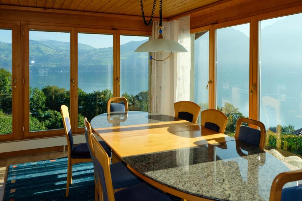 a dining room with a table and chairs and windows at Villa Nora in Faulensee