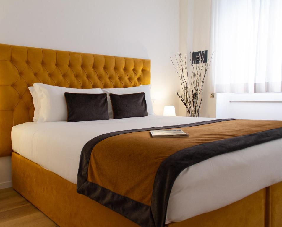 a bedroom with a large bed with a yellow headboard at Michelangelo Vatican Rooms in Rome