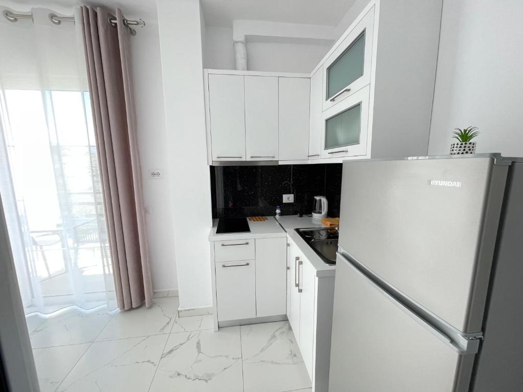 a white kitchen with white cabinets and a refrigerator at Villa Denis Ksamil in Ksamil