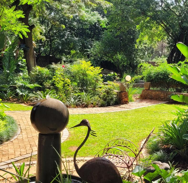 a statue of a bird on a post in a garden at Pandora's Guest Lodge in Klerksdorp