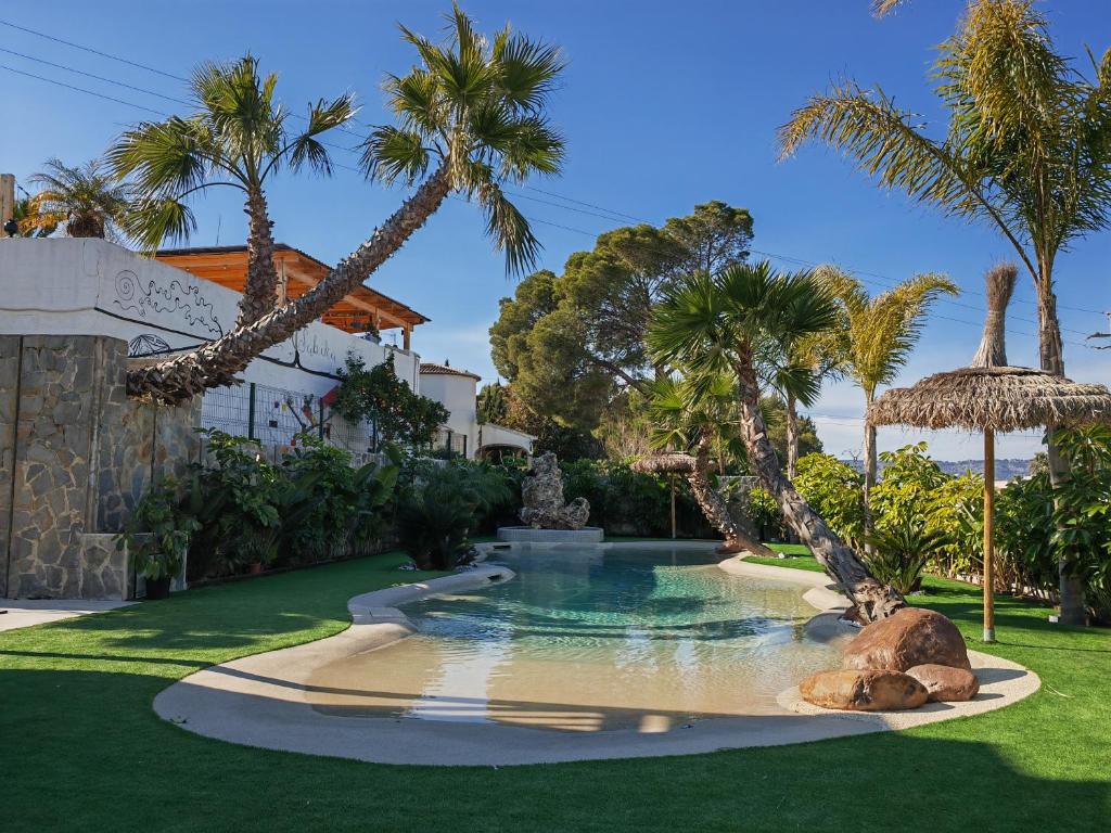 a swimming pool in a yard with palm trees at Hotel Casa Lili in Jávea