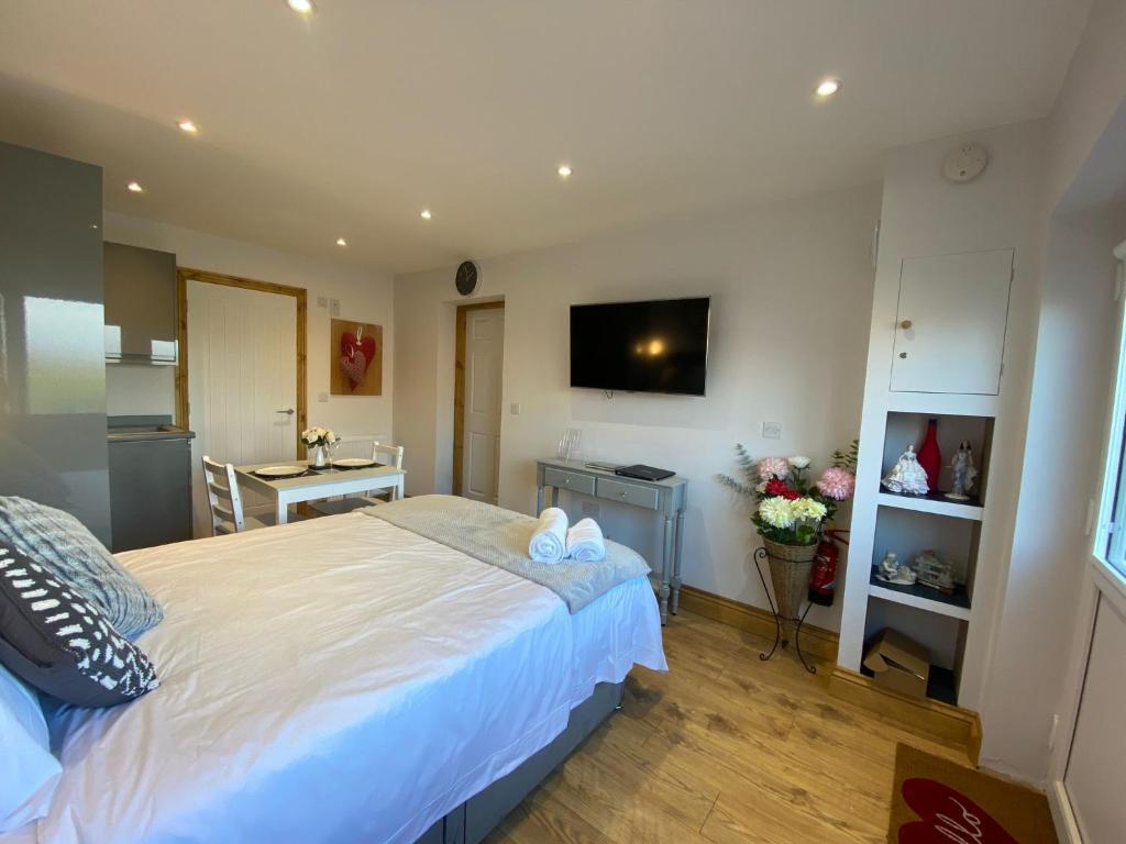 a bedroom with a large white bed and a kitchen at Beautiful 1-Bed studio in Penrith in Penrith