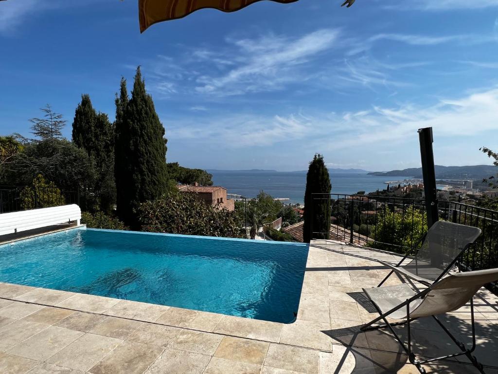a swimming pool with a chair and a view of the ocean at La Villa Pavilou in Le Lavandou