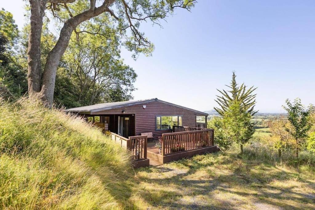 a log cabin with a deck on a hill at Grove Lodge, Contemporary Cabin in Mendip Hills in Axbridge