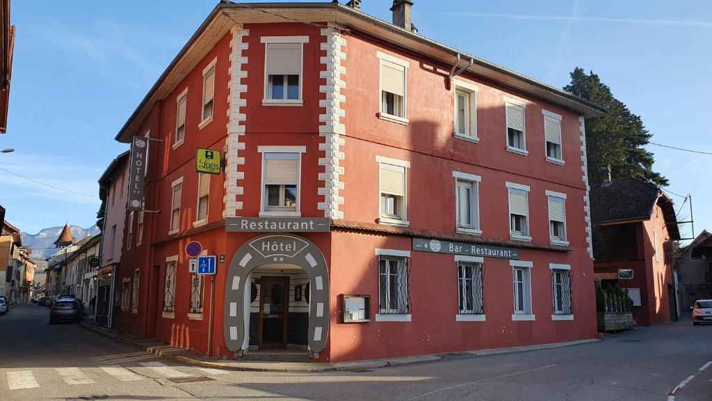 a red building on the side of a street at Logis Hôtel du Fer à Cheval in Yenne