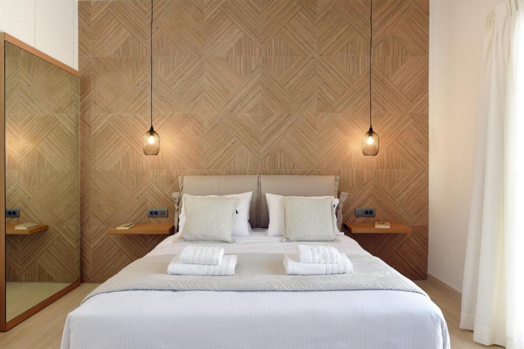 a bedroom with a large white bed with two pillows at Natal Suites in Ermoupoli