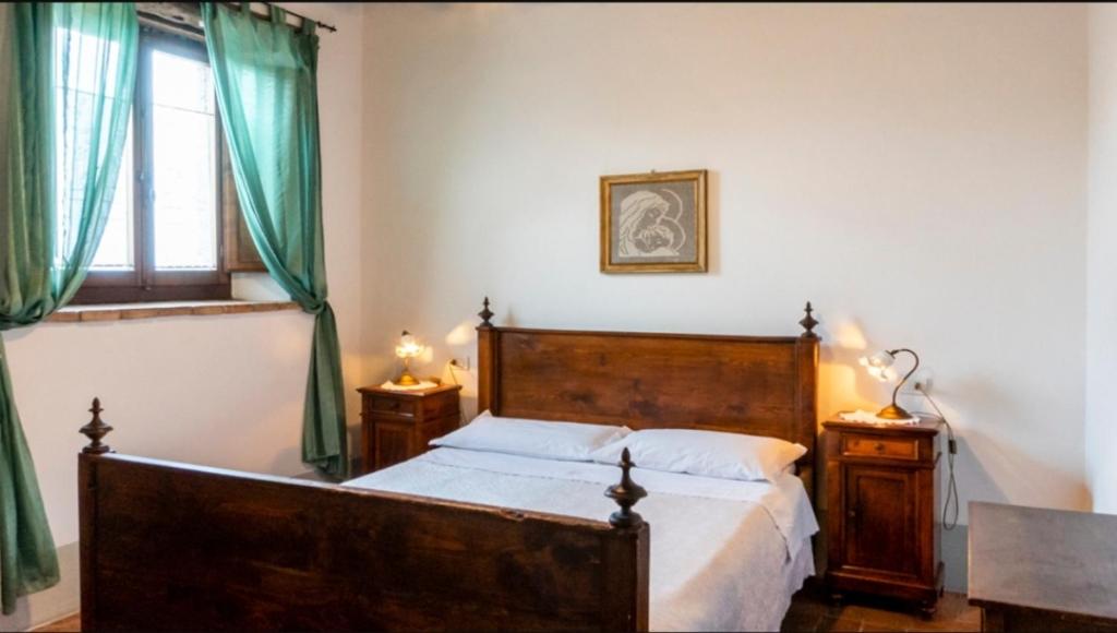 una camera con letto in legno e tende verdi di Agriturismo San Rocco Verucchio a Verucchio