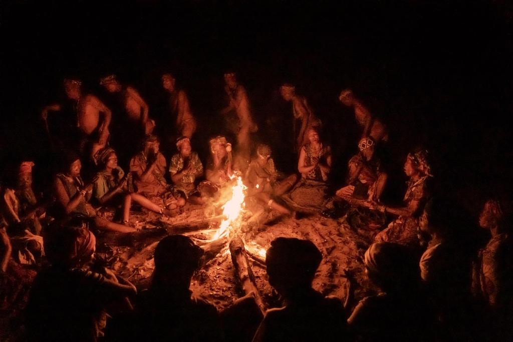 un grupo de personas sentadas alrededor de un fuego en Nhoma Safari Camp, en Tsumkwe